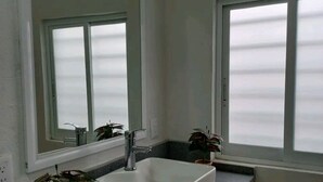 A bathroom with a white sink, a mirror, and a window.