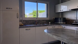 Een moderne keuken met een groot raam, witte kasten en een gebogen aanrecht.