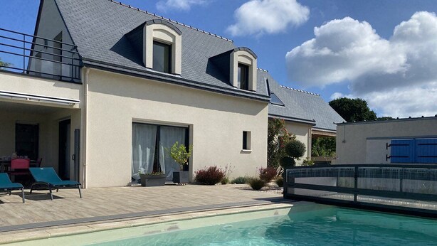 Een tweelaags huis met een zwembad, een overdekte patio en een garage.