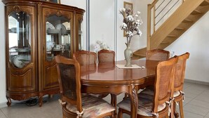 Een eetkamer met een houten tafel en stoelen, een glazen kast en een trap.