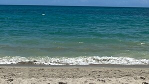 A beach with clear blue water and a sandy shore.