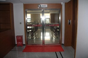 Entrada de hotel con alfombra roja, puertas dobles y un letrero sobre ellas.
