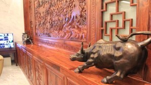 Un comptoir d’accueil orné d’une sculpture en bronze représentant un taureau, un mur décoratif aux motifs complexes et un motif géométrique chinois traditionnel.