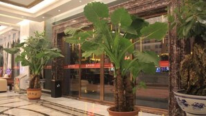 Un hall d’entrée agrémenté de plantes en pot, doté d’un sol en marbre et comprenant un espace de réception avec des portes en verre.