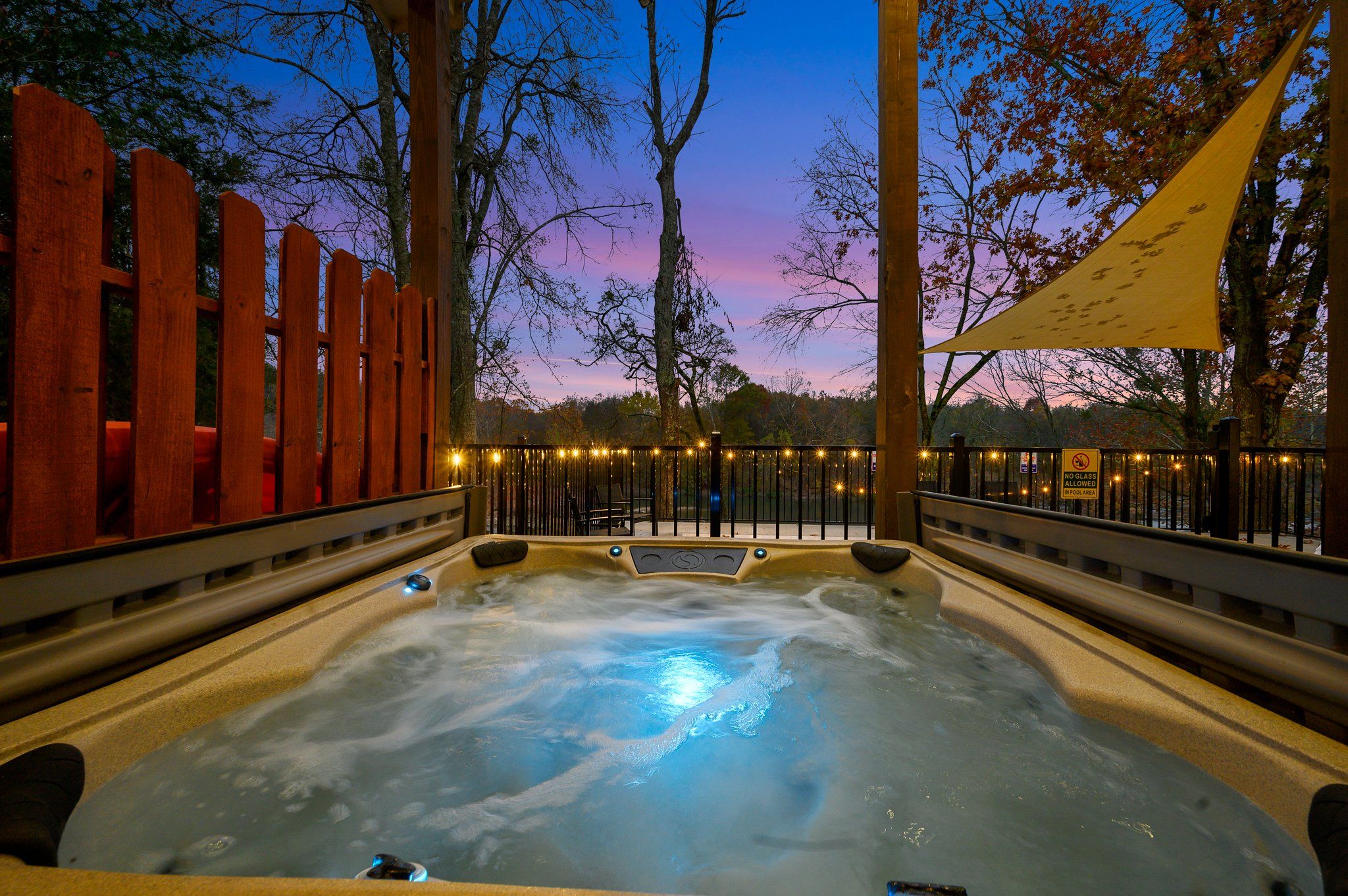 Un jacuzzi con cerco de madera y árboles al fondo.