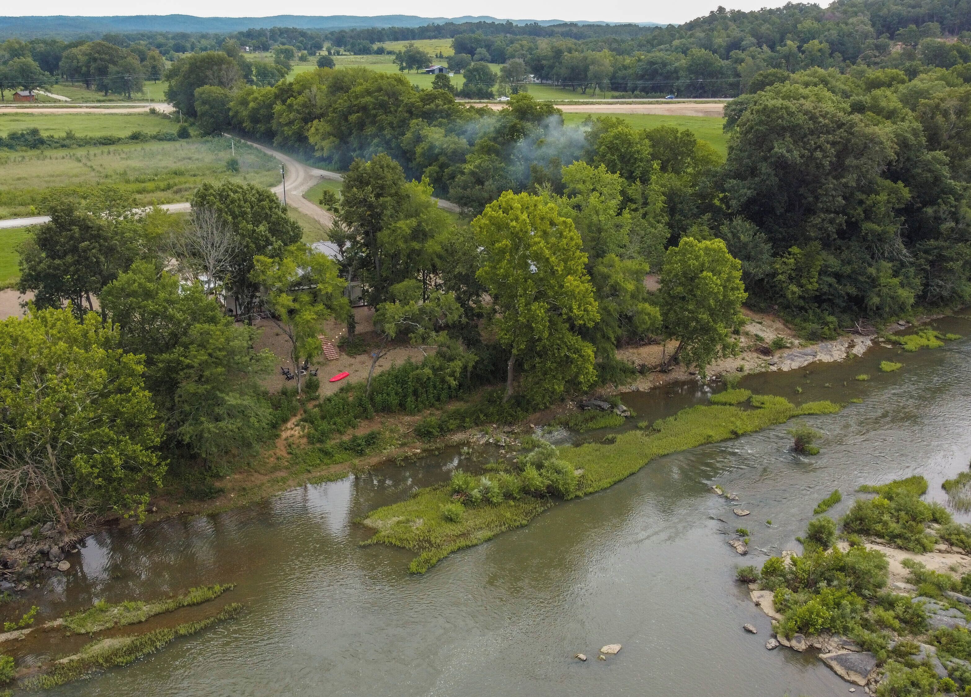 A river with a forested area and a dirt path.