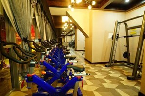 Un gimnasio con bicicletas estáticas, una zona de levantamiento de pesas y un suelo con estampado en zigzag.