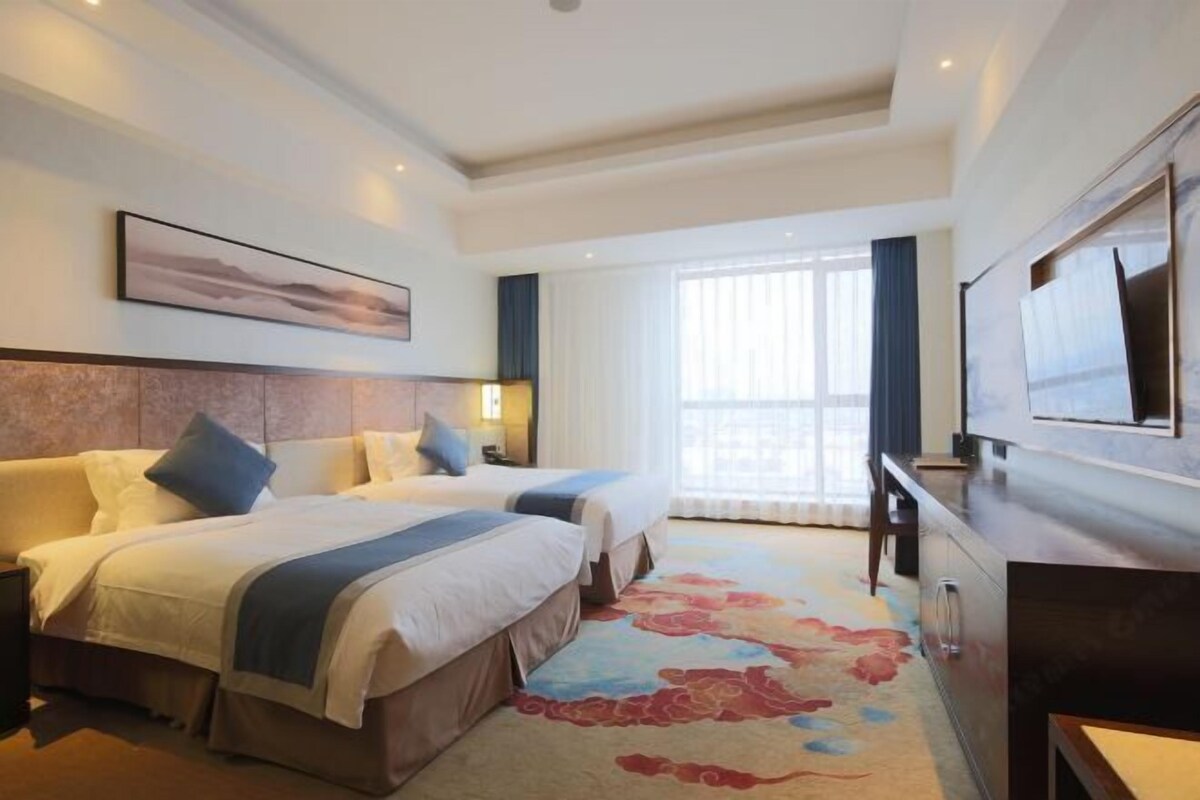 Een hotelkamer met twee bedden, een groot raam, een flatscreen televisie en een vloerbedekking.