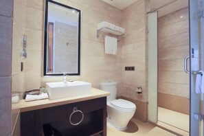 Een moderne badkamer met een wastafel, toilet en een douchecabine met glazen wanden.