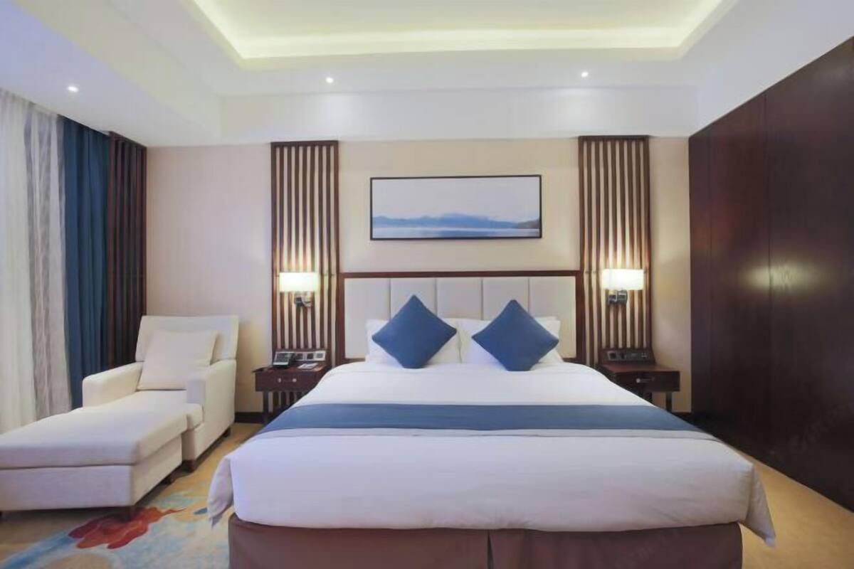 Une chambre d’hôtel avec un lit, une chaise, un bureau et une table de chevet.