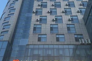 A multi-story building with a modern architectural design, featuring a series of windows and air conditioning units. - Xiyue wanda Hotel (Xiuyan)