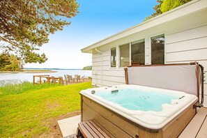 A hot tub in front of a house with a view of a lake. - Waterfront retreat with private beach, cookhouse, hot tub, EV charger, & firepit (Gig Harbor)