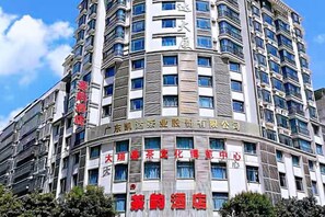A multi-story hotel with signage indicating a business center and a restaurant. - Chayun Hotel (Dabu)