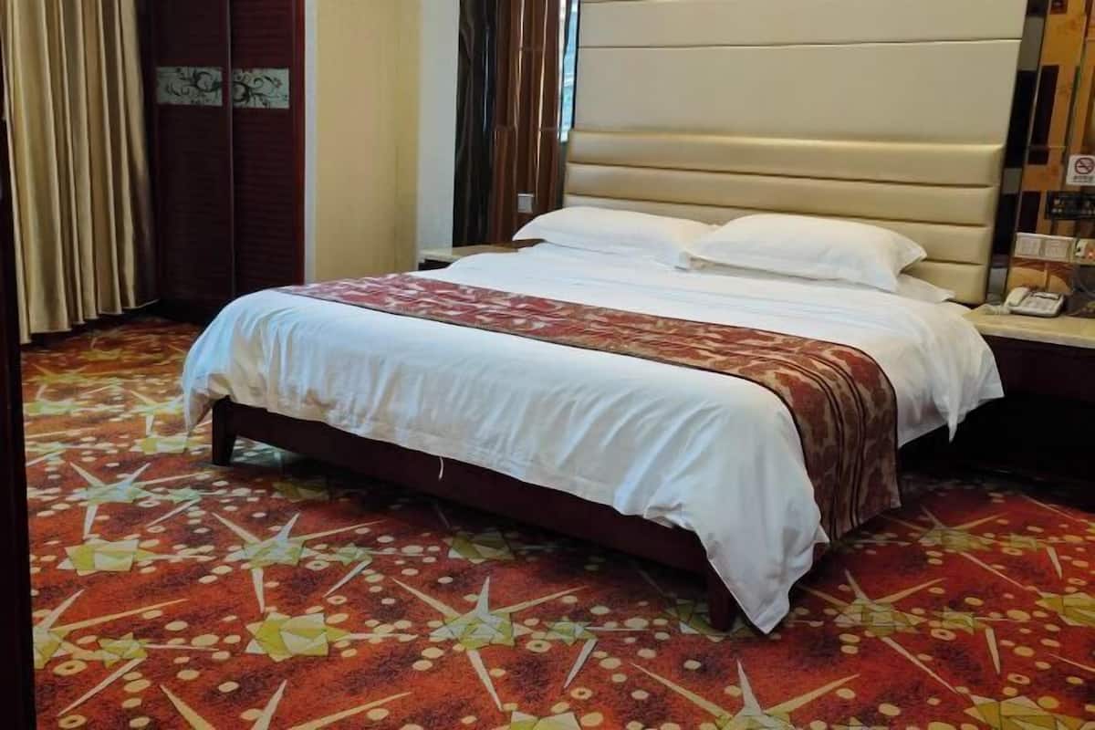 A hotel room with a bed, a telephone, and a patterned carpet.