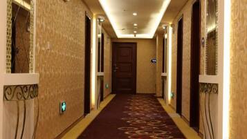 Un pasillo de hotel con piso alfombrado, puertas a ambos lados y una lámpara en el techo.