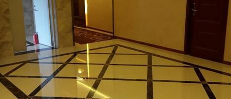 A hotel lobby with a polished floor, a reception area, and a door.