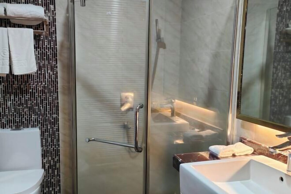 A modern bathroom with a glass shower enclosure, a white sink, and a tiled backsplash.
