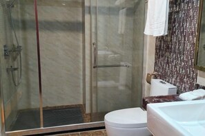 A modern bathroom with a glass shower enclosure, a white toilet, and a marble countertop. - Chayun Hotel (Dabu)