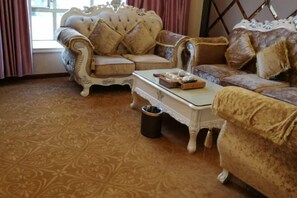 A room with a patterned carpet, a white coffee table, and two ornate sofas with cushions. - Chayun Hotel (Dabu)