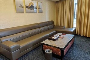 Una habitación de hotel con un sofá de cuero marrón, una mesita de centro de mármol y un cubo de basura.