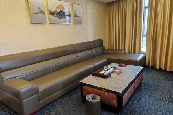 A hotel room with a brown leather sofa, a marble coffee table, and a trash can. - Chayun Hotel (Dabu)