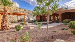 A landscaped outdoor area with a pool, palm trees, and a building with arched walkways. - 60-acre custom home with breathtaking views of city of Las Cruces & Organs! (Las Cruces)