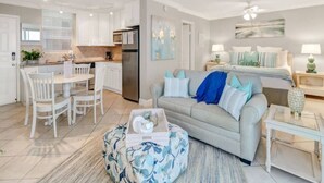 A modern apartment with a dining area, kitchenette, and a living room with a sofa and a coffee table.