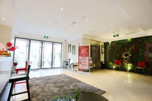 Un vestíbulo de hotel con mostrador de recepción, zona de estar y una pared con jardín vertical.