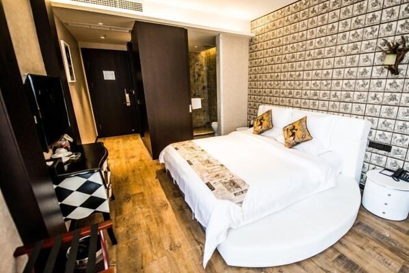 Habitación de hotel con cama, escritorio, silla y baño visible a través de una puerta abierta.