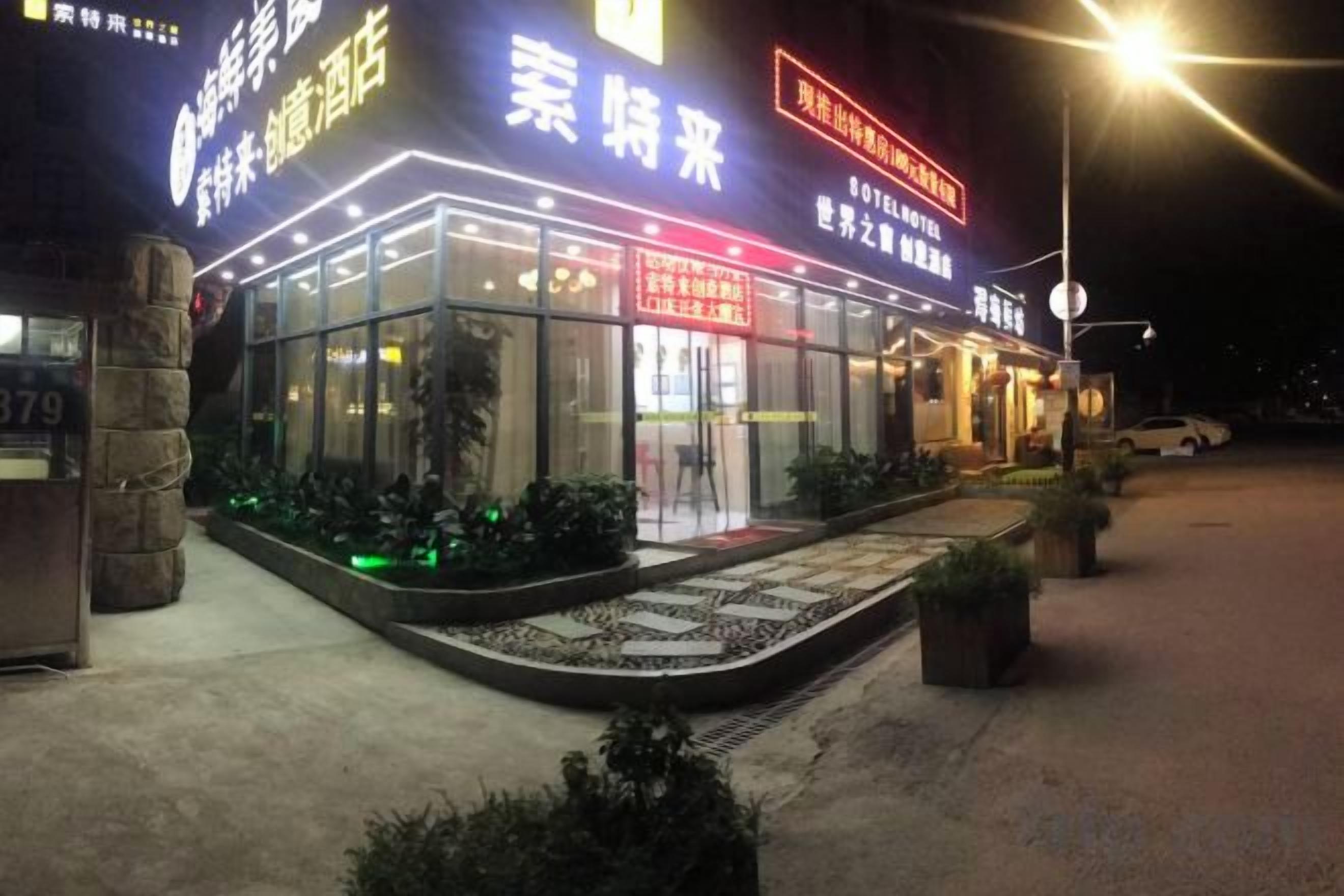 A hotel with a glass facade, illuminated signage, and a well-lit entrance.