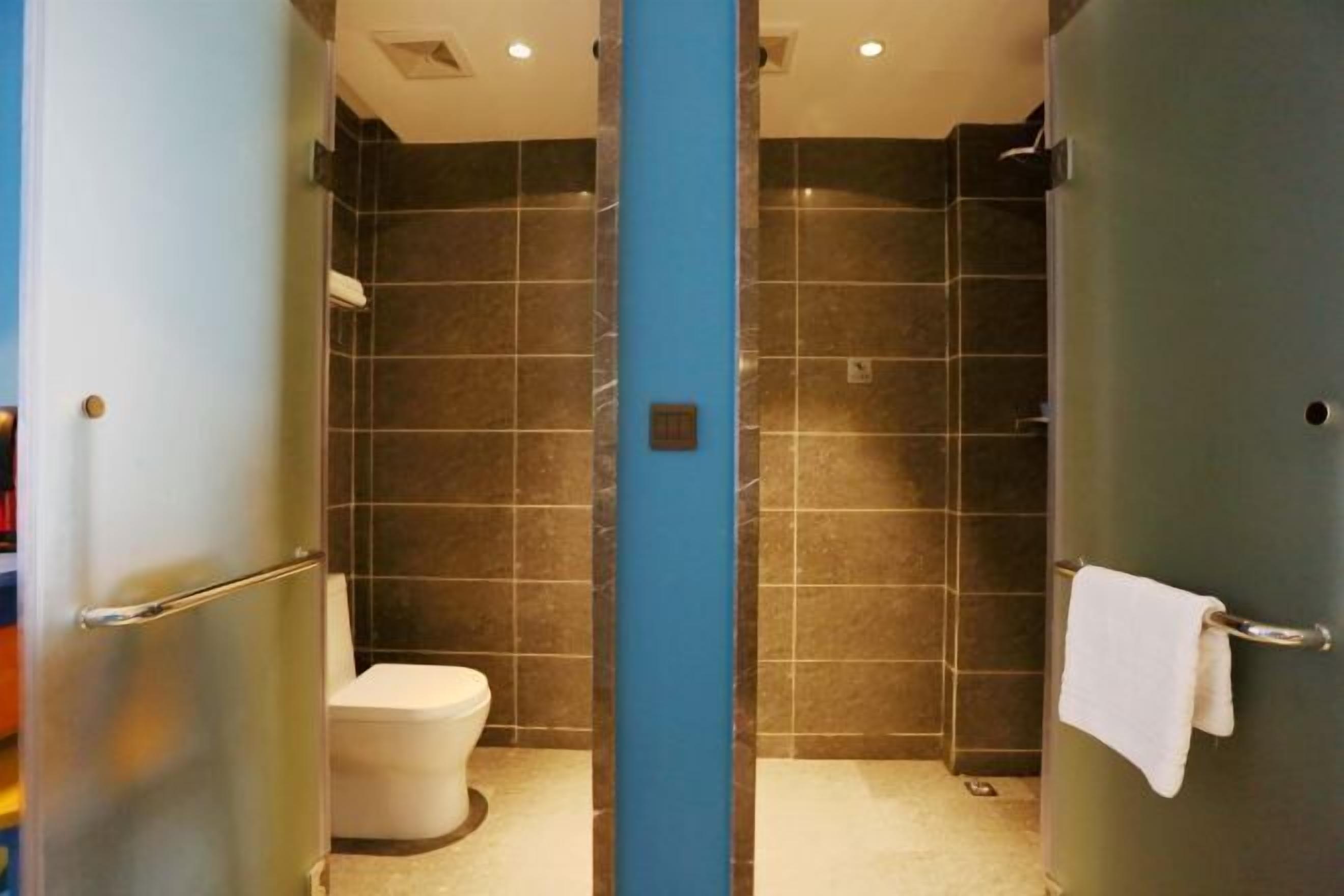A bathroom with a toilet, a shower, and a towel rack.