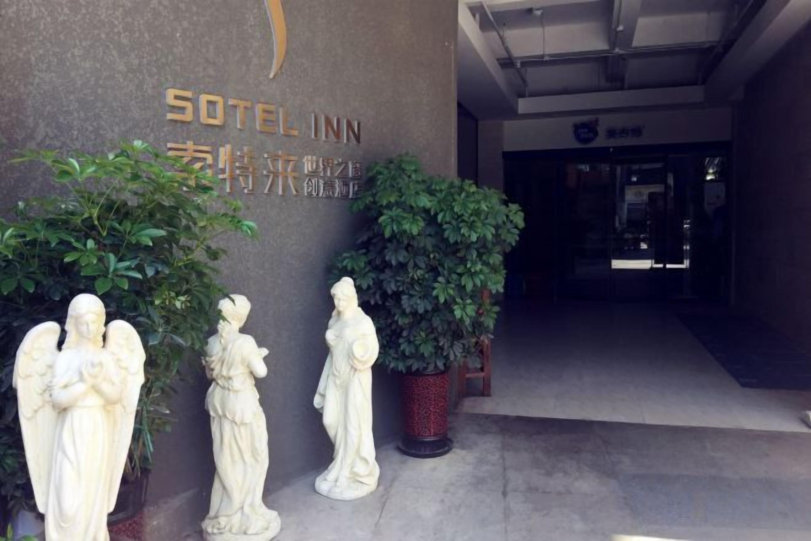 La entrada a un hotel con un letrero que dice 'Sotel Inn' y una planta en maceta.