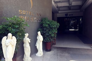 The entrance to a hotel with a sign reading 'Sotel Inn' and a potted plant.