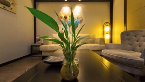 A modern room with a glass vase on a table, a sofa, and a lamp. - Sotel Inn (Wenzhou Xincheng Convention and Exhibition Center) (Wenzhou)