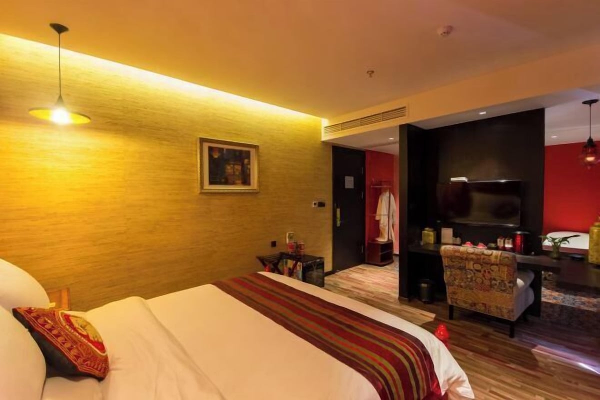 Habitación de hotel con una cama grande, un escritorio, una silla y un televisor.