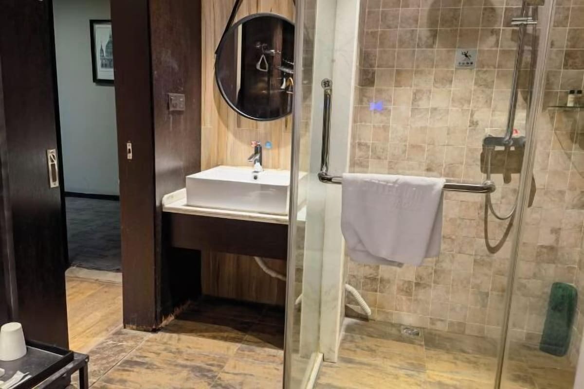 Un baño con cabina de ducha de vidrio, un lavabo con espejo y un perchero para toallas.