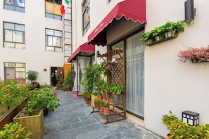 Un callejón estrecho con plantas en macetas y un toldo rojo.