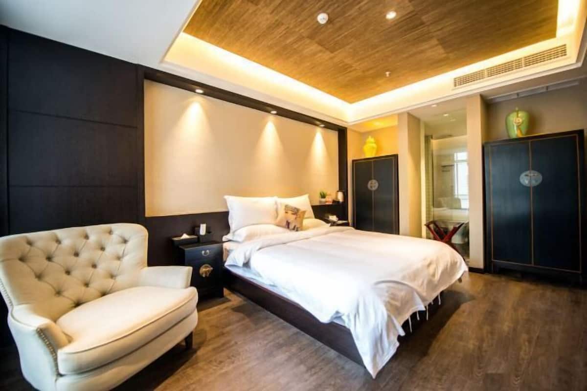 A modern bedroom with a bed, a chair, a wardrobe, and a nightstand.
