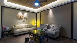 A modern living room with a sofa, two armchairs, a coffee table, and a ceiling fan. - Sotel Inn (Wenzhou Xincheng Convention and Exhibition Center) (Wenzhou)
