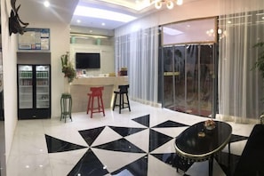A modern hotel lobby with a geometric black and white floor pattern, a bar area, and a refrigerator with beverages. - Sotel Inn (Wenzhou Xincheng Convention and Exhibition Center) (Wenzhou)