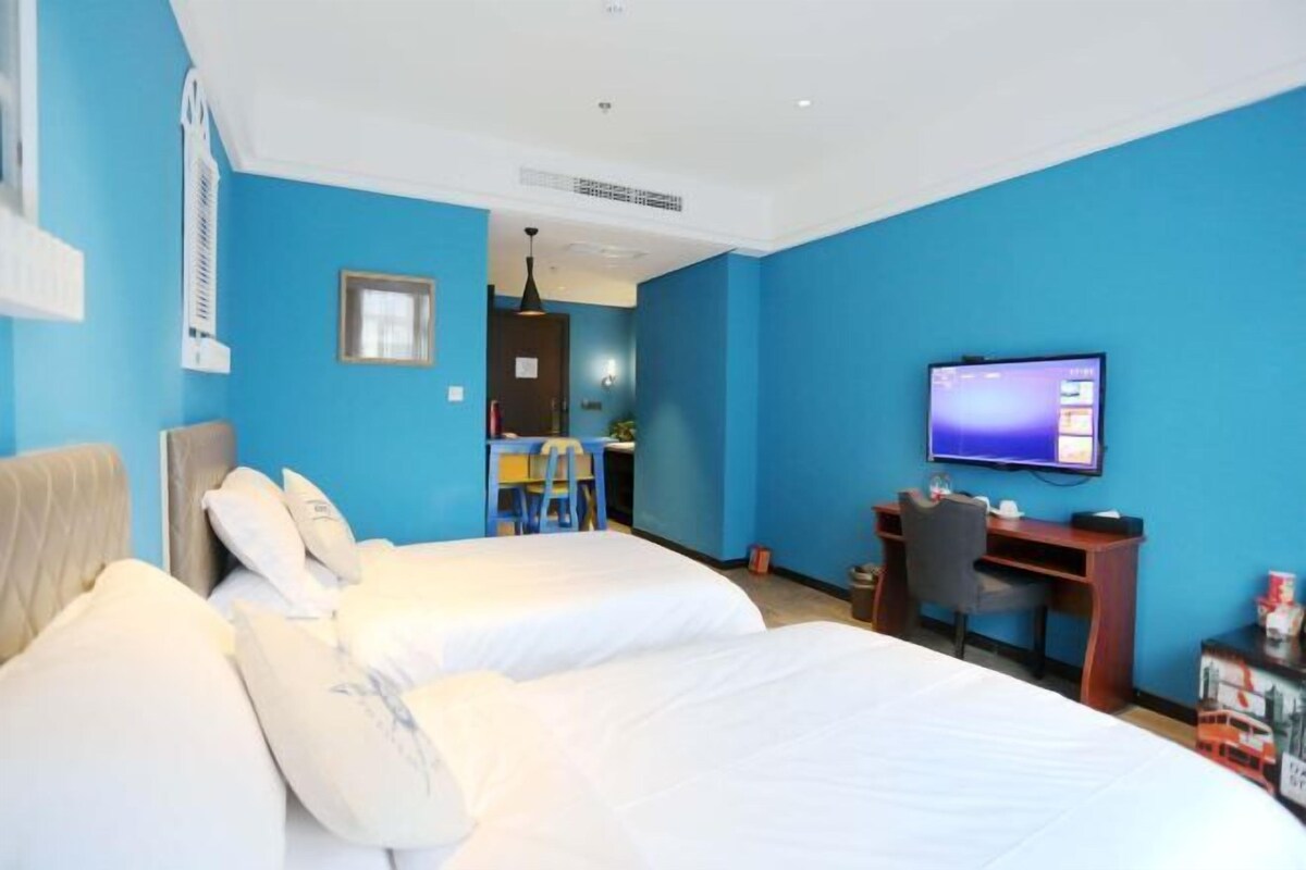 Una habitación de hotel con dos camas, un escritorio, una silla, un televisor y una mesita.