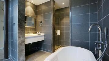 A modern bathroom with a bathtub, a sink, and a glass-enclosed shower.