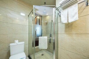 Un baño moderno con ducha de vidrio, inodoro y un perchero con toallas.