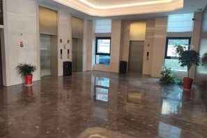 A spacious lobby with a polished floor, elevators, and potted plants. - Riverside Garden Hotel (Taicang)