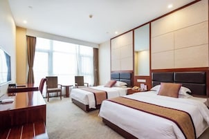 Habitación de hotel con dos camas, un escritorio, una silla y un ventanal amplio.