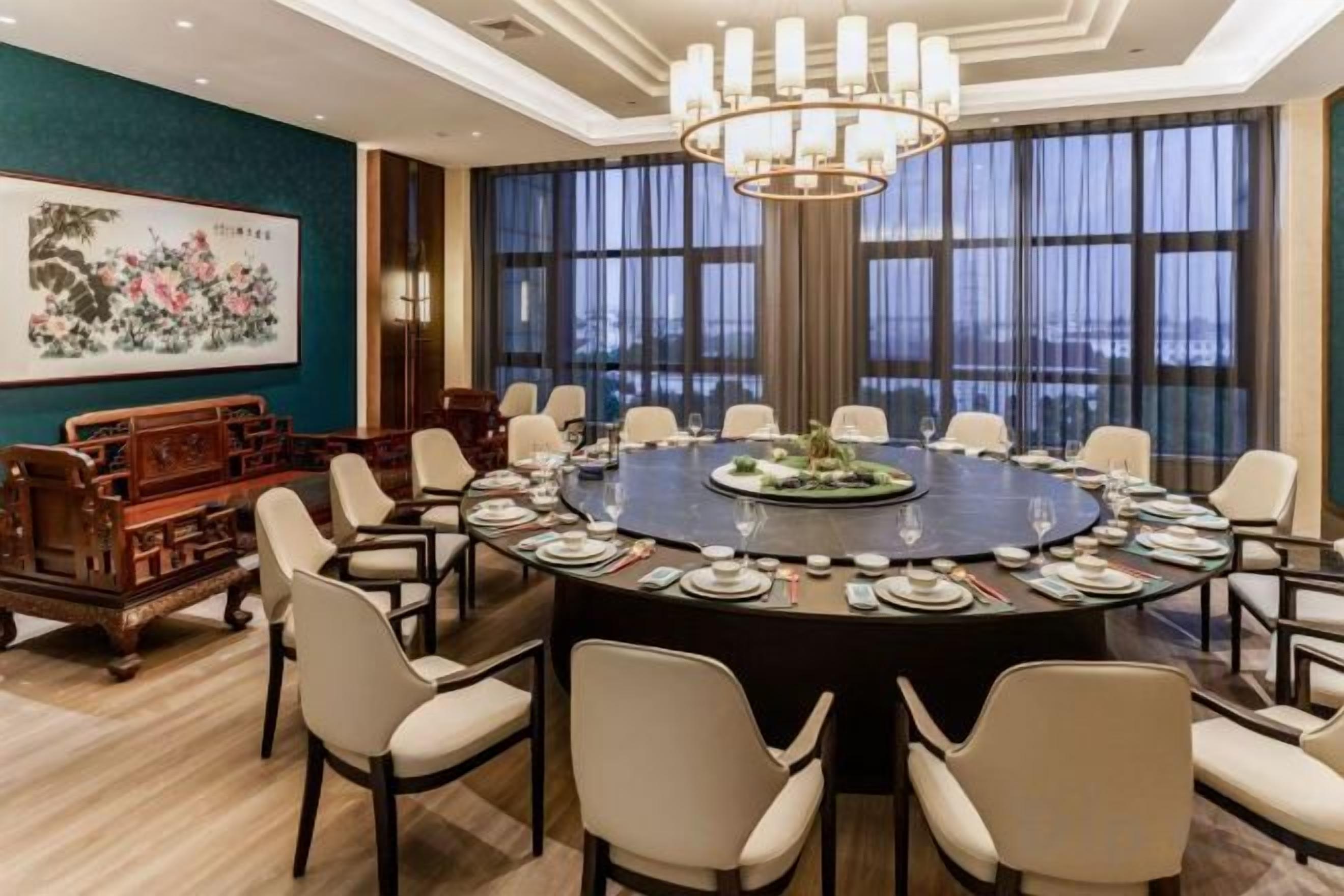A conference room with a round table, chairs, and a chandelier.