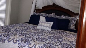 Un dormitorio con cama con dosel, ventilador de techo y una planta decorativa.