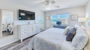 Un dormitorio con cama, cómoda, televisor y ventana con vistas.