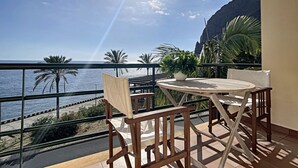 A balcony with a view of the sea, a table, chairs, and potted plants. - Sunny Side by Atlantic Holiday (Madalena do Mar)