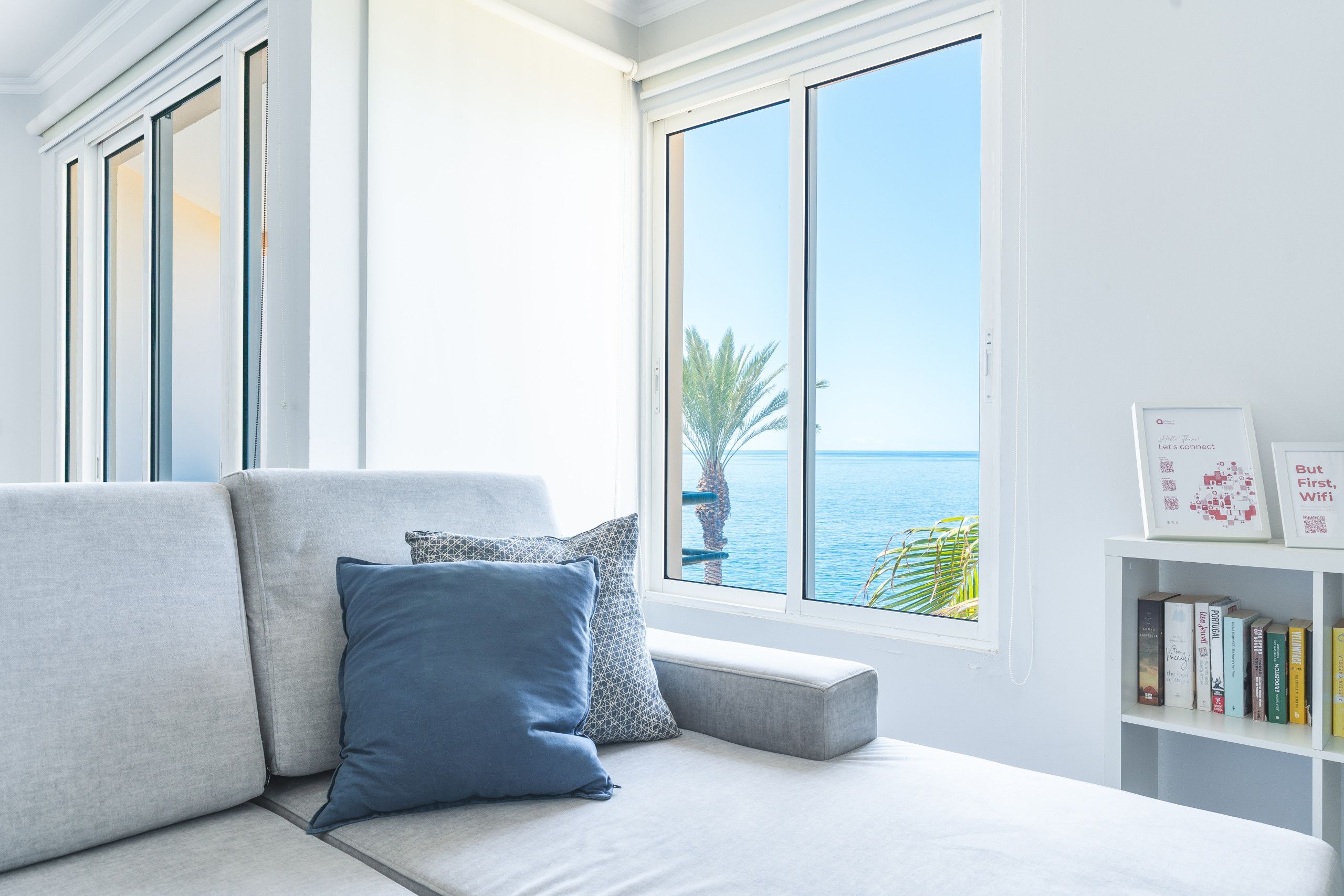 Ein modernes Wohnzimmer mit einem grauen Sofa, einem blauen Kissen und einem Bücherregal mit Büchern.